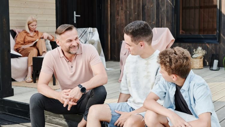 Family sharing quality time on a wooden terrace. Smiling and conversing.